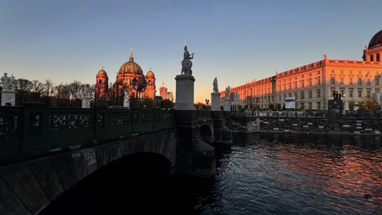 La Spree à Berlin au coucher du soleil : le pont du Château, la cathédrale de Berlin et la façade du Humboldt Forum éclairées de lumière orangée